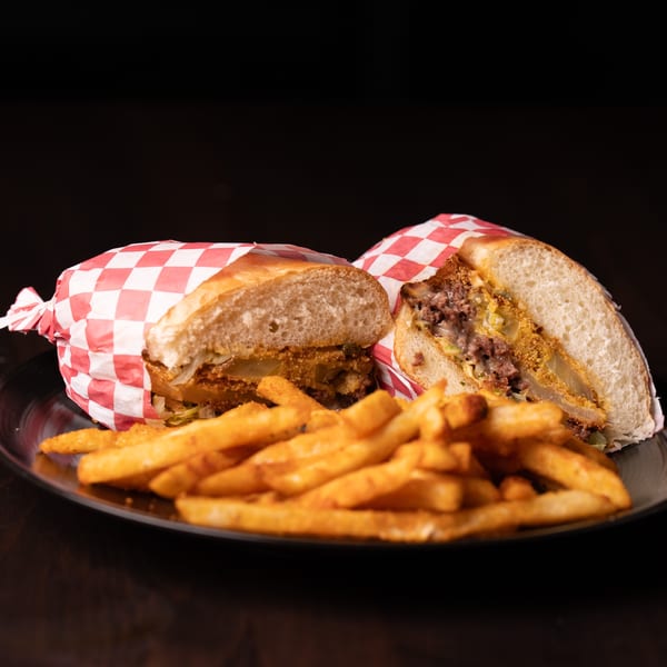 A Legion Sports Bar southern sandwich, cut in half, with fries on a dark plate.